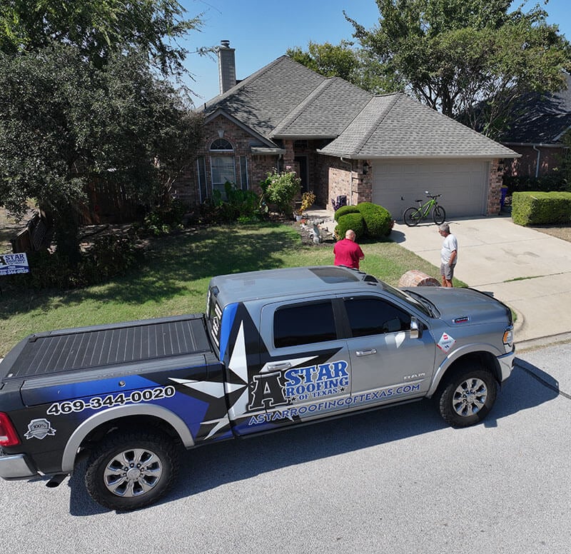 A Star Roofing truck and team parked in front of a house with a new roof